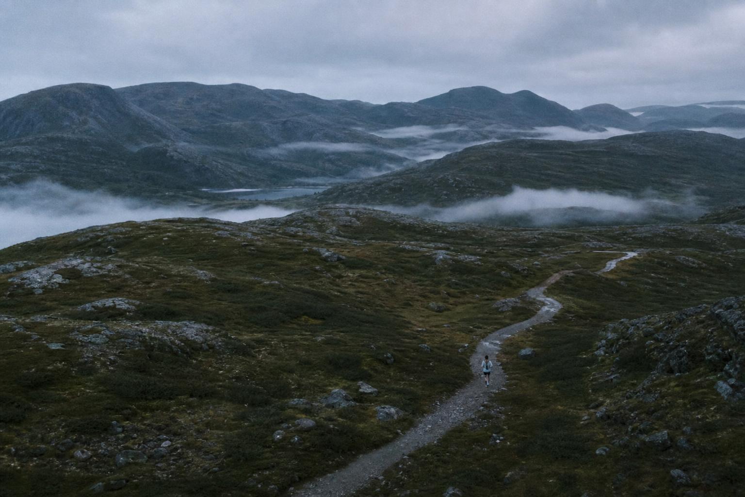 Ensom løper på en fjellsti i Norge ved morgenlys